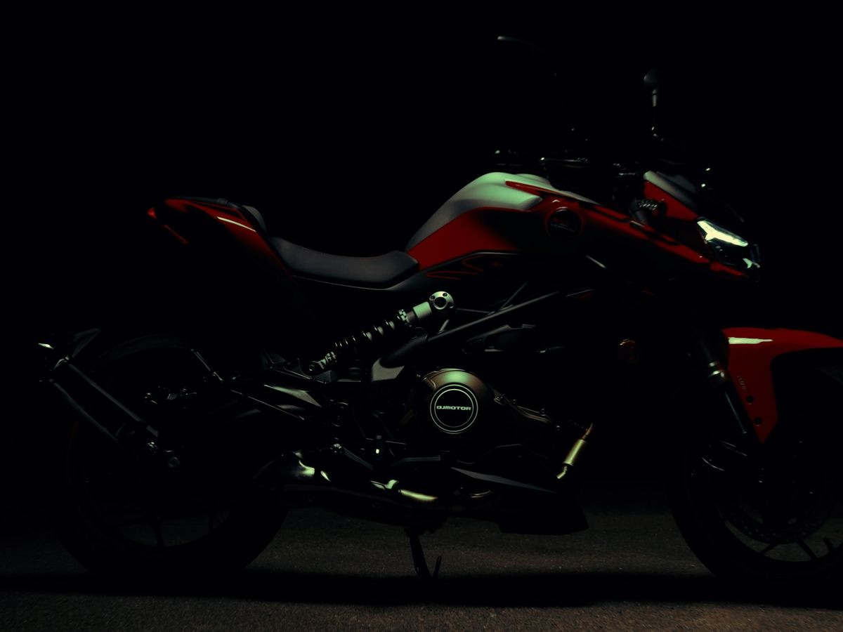 Moto routière rouge et noire éclairée en studio sur fond noir