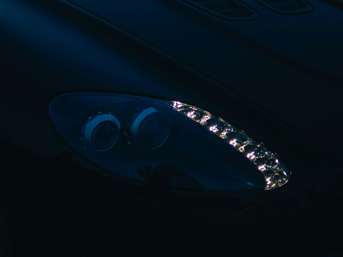 Détail d’un phare de voiture de sport noire, signature lumineuse dans la pénombre
